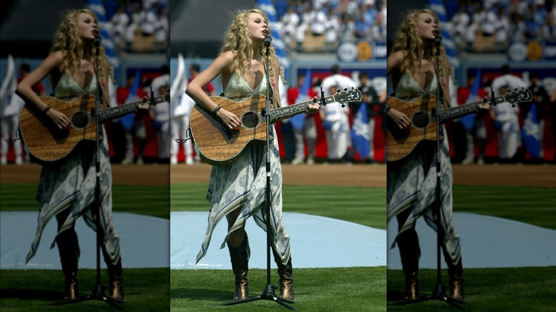 Taylor Swift performing with an acoustic guitar on a football field