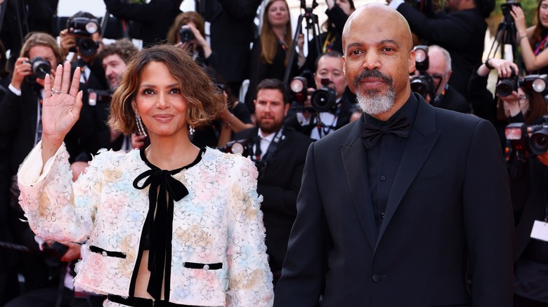 Halle Berry waving on the red carpet while standing next to Van Hunt