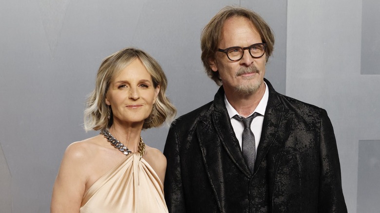 Helen Hunt and Jeffrey Nordling posing on the red carpet together in front of a gray backdrop