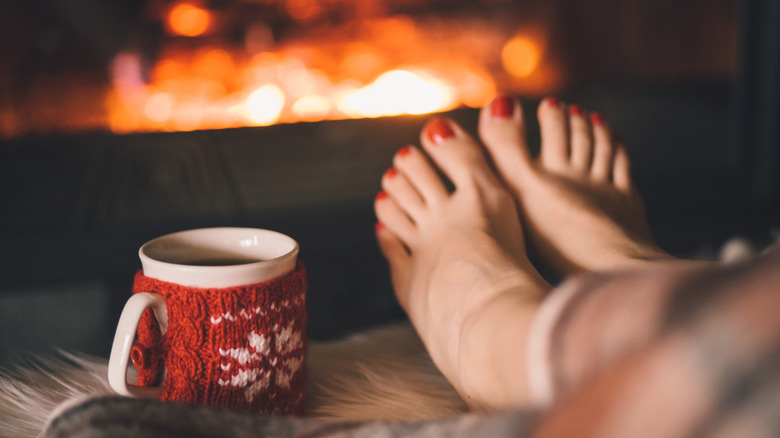 Feet in front of a Christmas tree with a festive manicure
