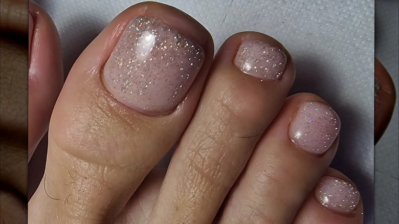 Feet with a nude, glitter pedicure