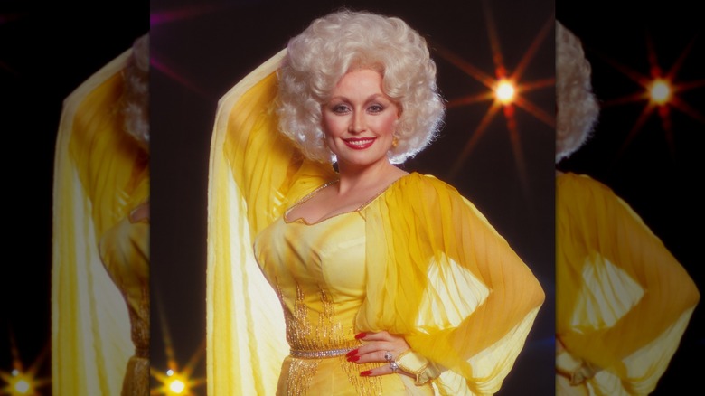 Dolly Parton in yellow with red nails