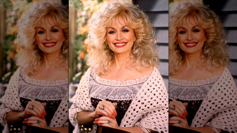 Dolly Parton in a frilly dress with long red nails