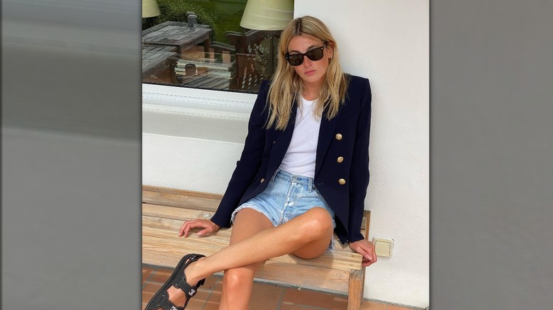A woman in a blue blazer and denim shorts 