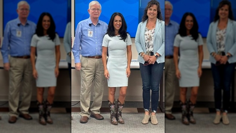 Lauren Boebert in a pale blue dress and cowboy boots, standing between two people