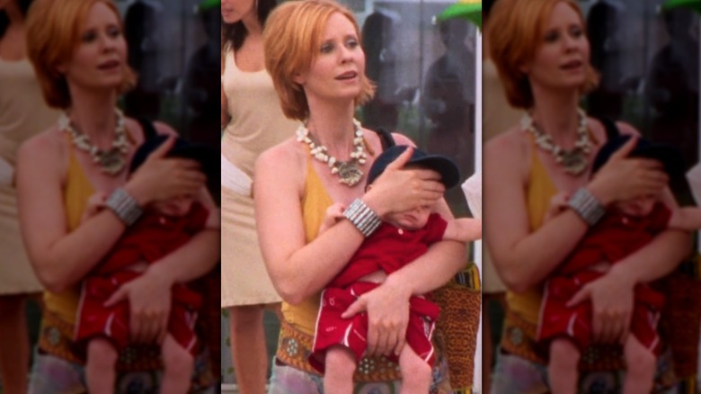Cynthia Nixon as Miranda Hobbs Jones wearing an orange top and pearl necklace