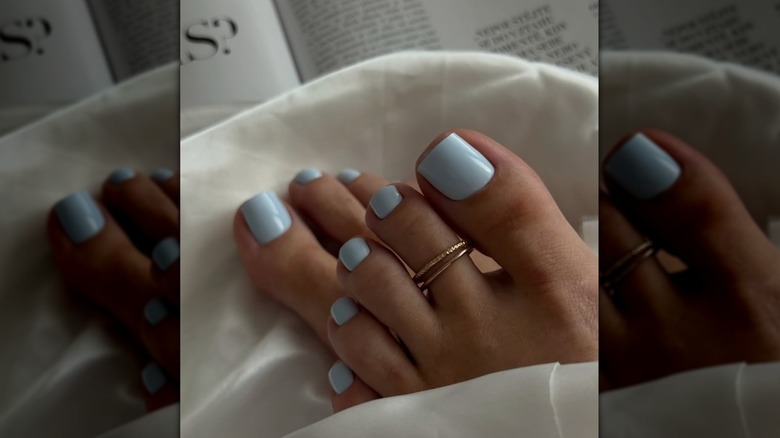 A close-up of a baby blue pedicure with toe rings