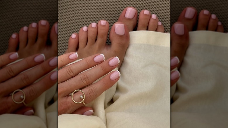 A woman with a pink pedicure and French tip manicure wearing white