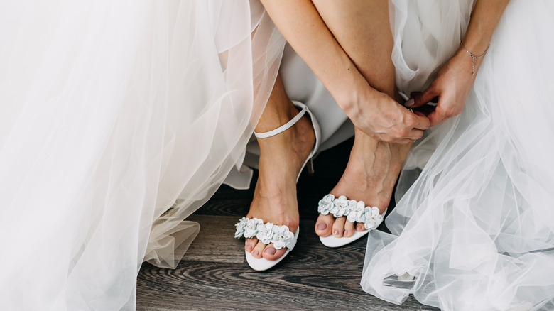 A bride putting on her shoes on her wedding day