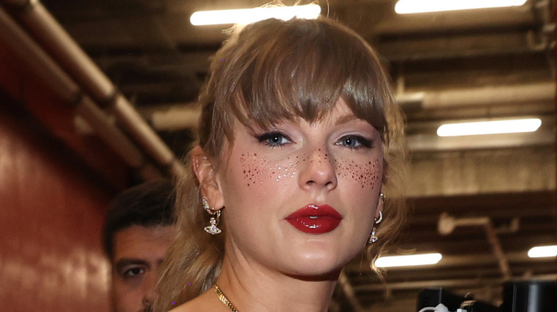 Taylor Swift with face glitter and red lips at a football event