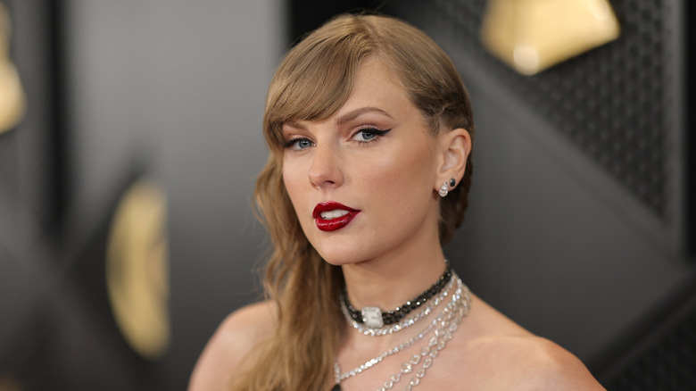 A close up of Taylor Swift at the Grammys with lots of necklaces on