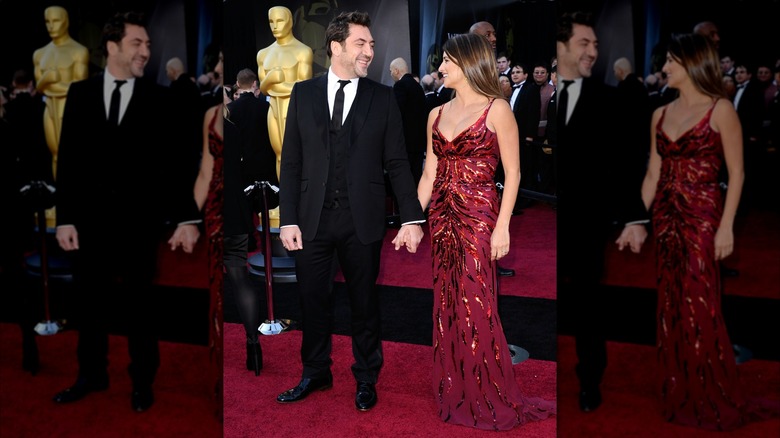 Penélope Cruz and Javier Bardem smiling at one another as they stand hand-in-hand on the red carpet