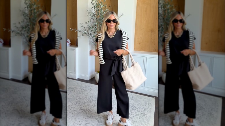 A woman on Instagram sharing a travel outfit idea in a black jumpsuit