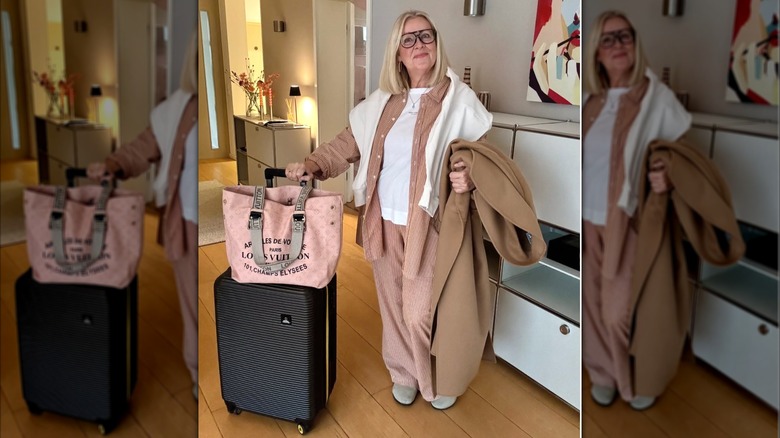 A woman in a peach matching suit with a white t-shirt and her suitcases with her