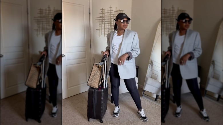 A woman with a ball cap, leggings and a grey blazer with her suitcases