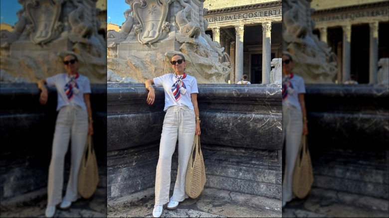 A woman in linen pants and white sneakers in front of a European fountain
