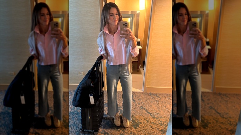 A woman wearing a pink shirt with jeans and a black suitcase on Instagram