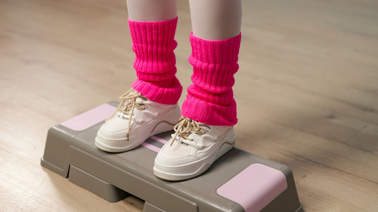 Person's legs in hot pink leg warmers on an aerobics stepper