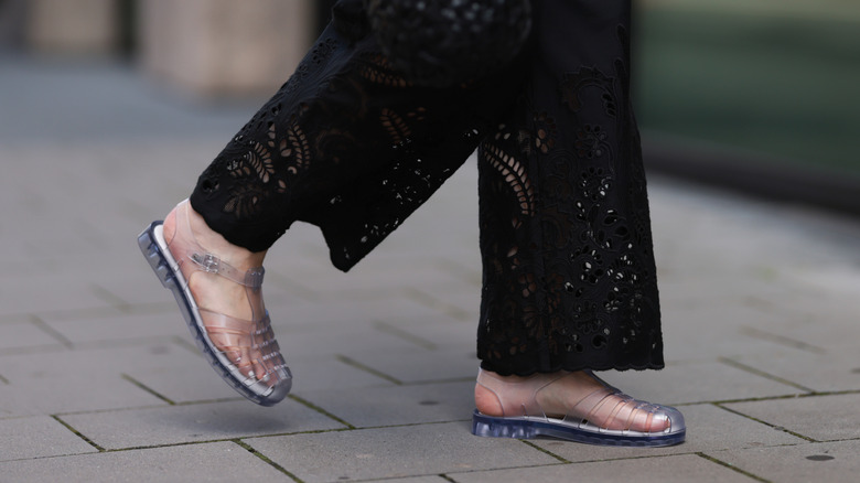Maria Barteczko seen wearing ARKET black embroidered wide leg trousers and Melissa Possession transparent Jelly fisherman sandals, on July 28, 2024