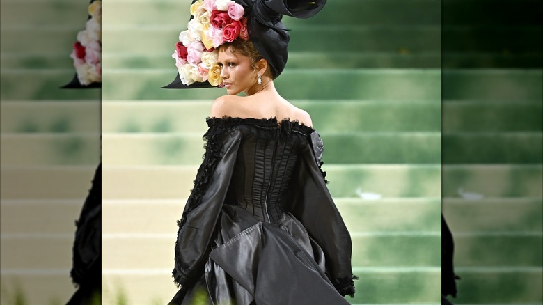 Zendaya at the Met Gala wearing a black gown and floral headpiece