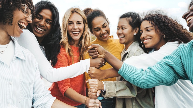 A group of women putting their fists together and smiling