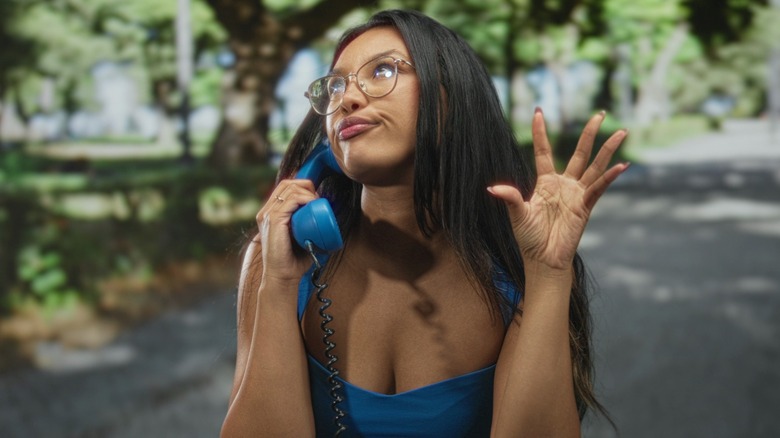 A woman pulling a sassy face while on a blue phone with her hand out