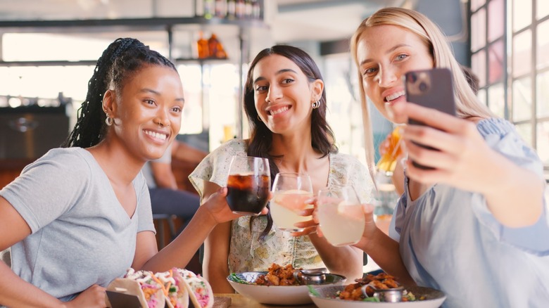 Three female friends taking a selfie at a table