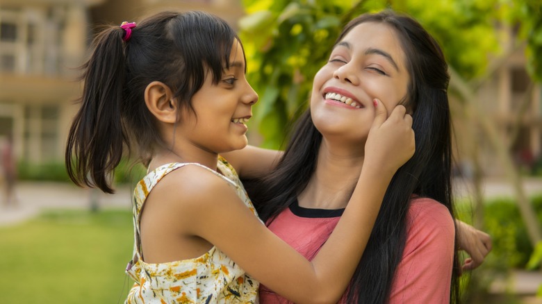 A younger girl pinching the cheek of a woman