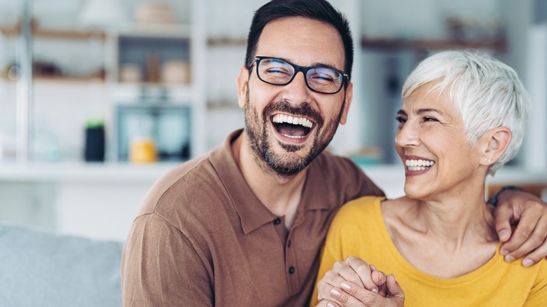 A man smiling with his arm around a woman, who's also smiling