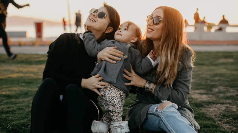 Two women sitting down while taking care of a young child