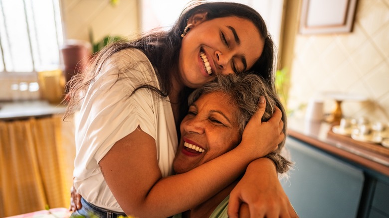 An older woman and younger woman smiling and hugging