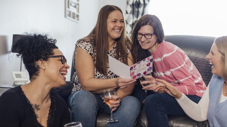 A group of women smiling while reading a birthday card