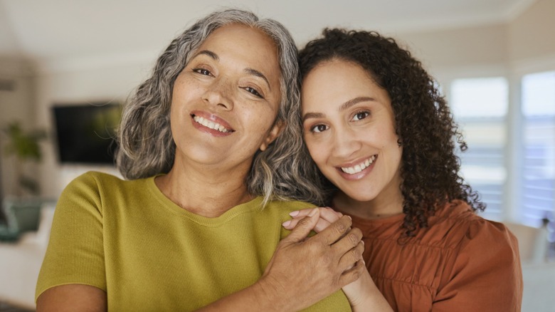 Two women smiling and holding hands with their heads together