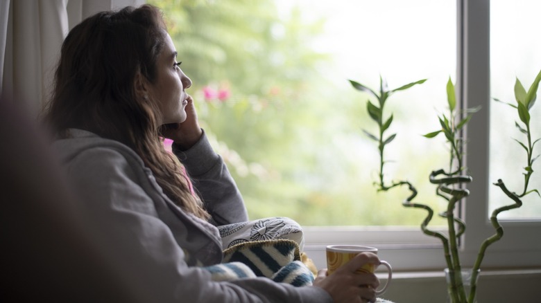 A woman with long hair looking longingly out a window