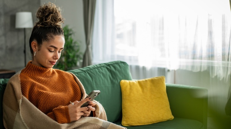 A woman looking at her phone while sitting on a sofa