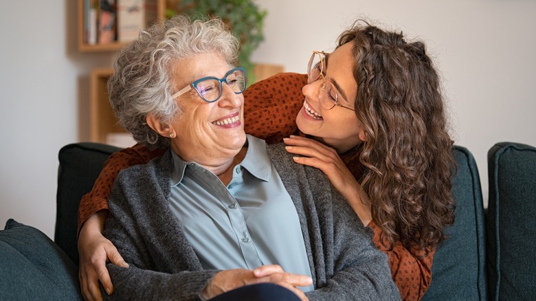 A woman embracing her grandmother as both smile