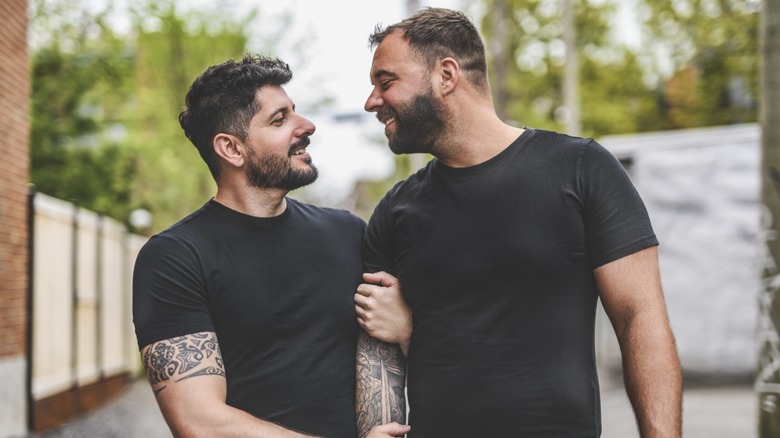 A gay couple walking down the street and looking at each other, both are wearing black shirts