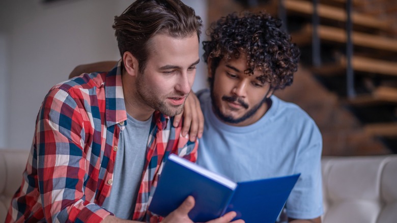 Two men reading a book together