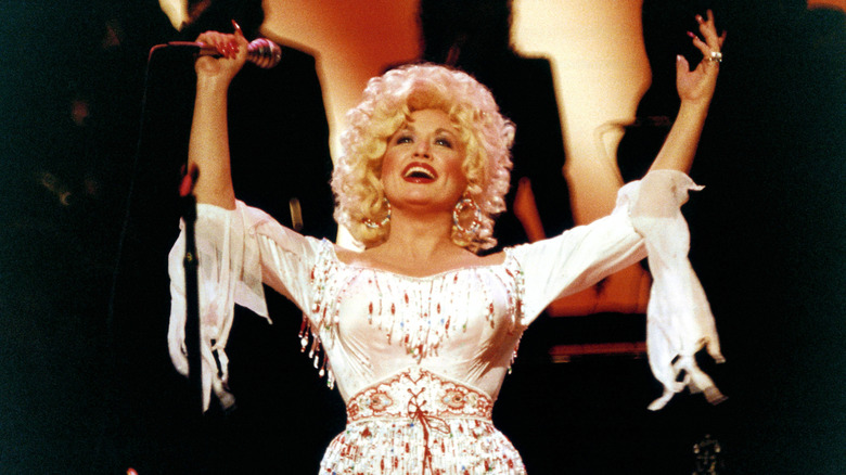 Dolly Parton smiling with her arms in the air