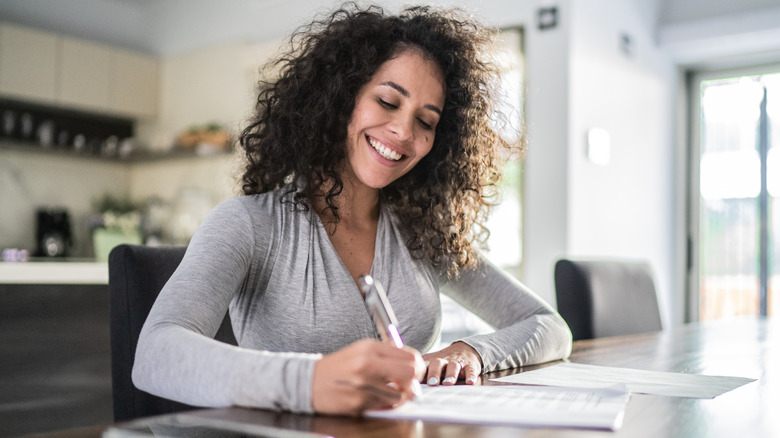 Woman smiling & writing on paper
