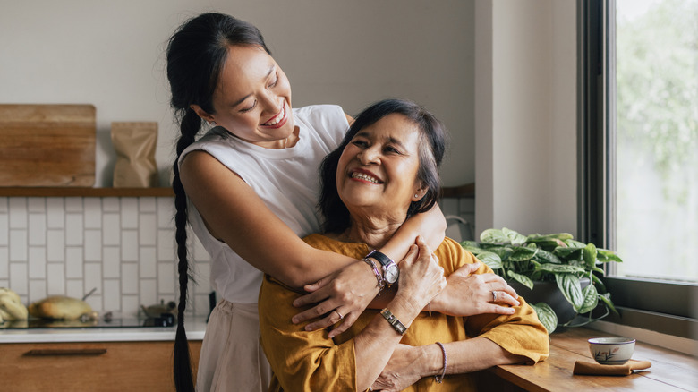 Woman hugging older woman & smiling