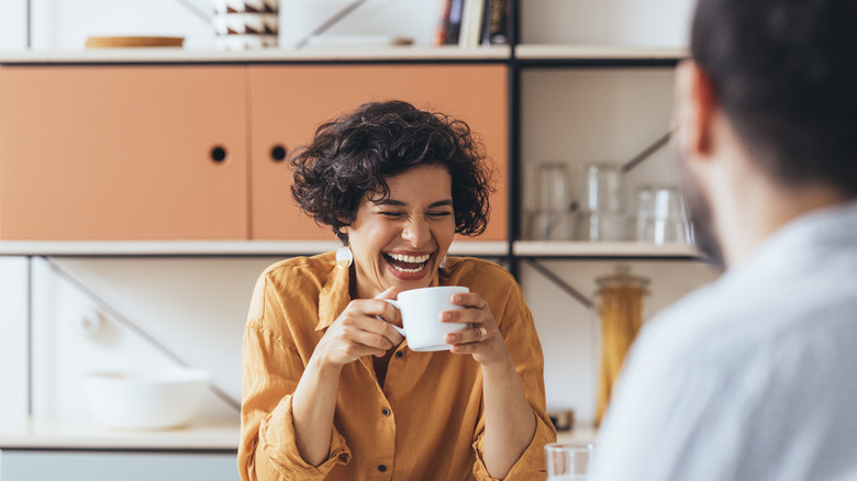 Woman holding mug & laughing