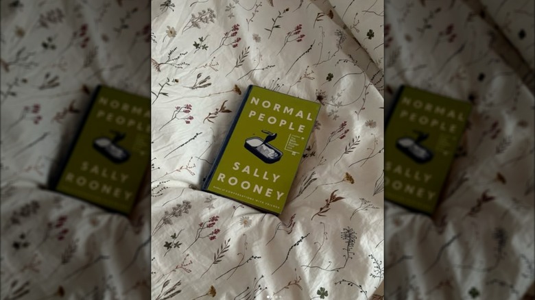 A copy of "Normal People" on a bed with a floral bedspread