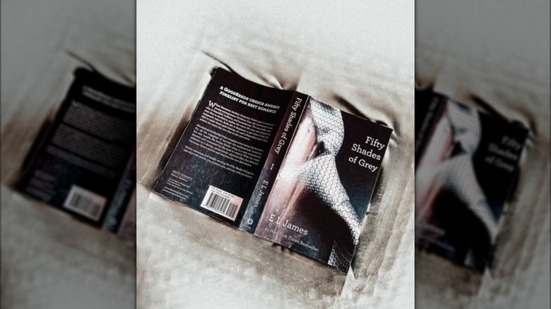 A copy of the novel "Fifty Shades of Grey" propped open on a bed