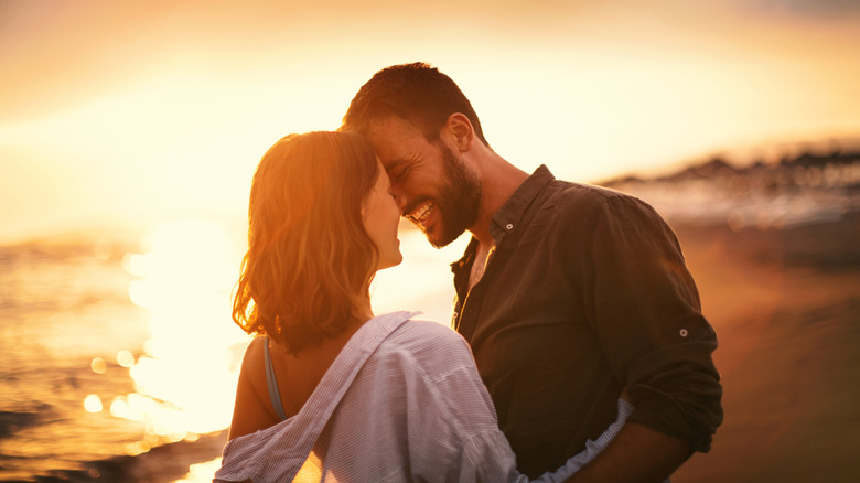 Young couple looking each other on the beach at late sunset.