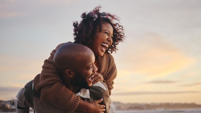man carrying smiling woman on his back