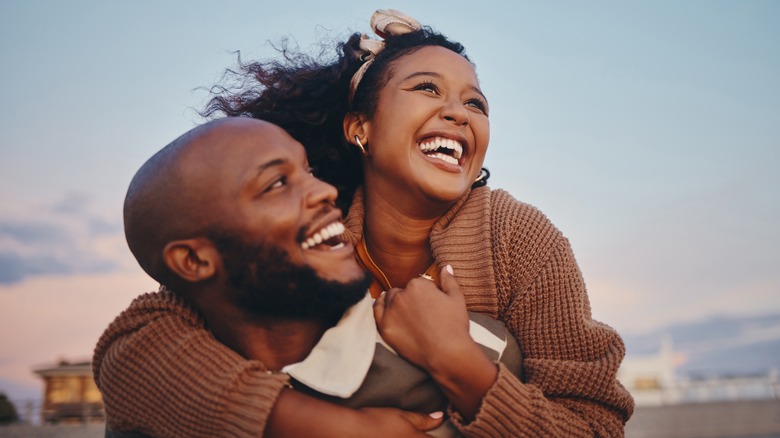 man and woman in an embrace, looking happy