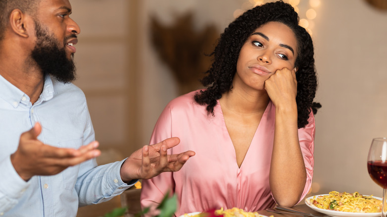 man talking to bored woman over meal