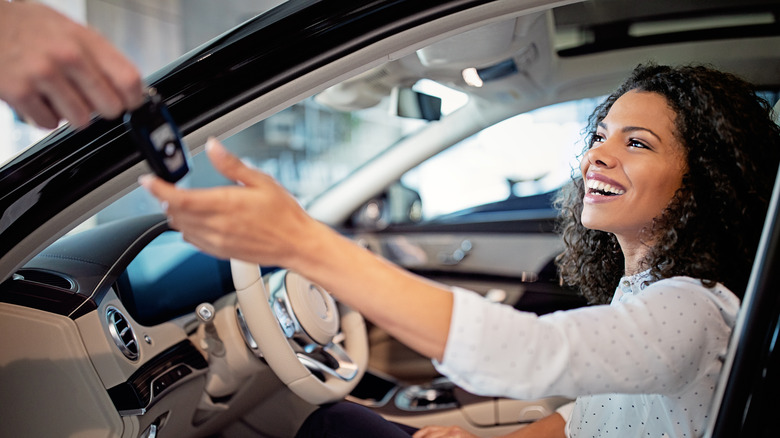Smiling woman getting the keys in her car