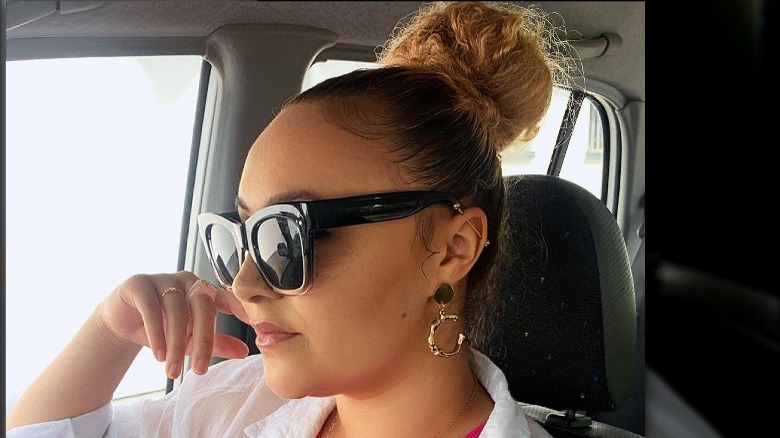 A woman in her car with a bun